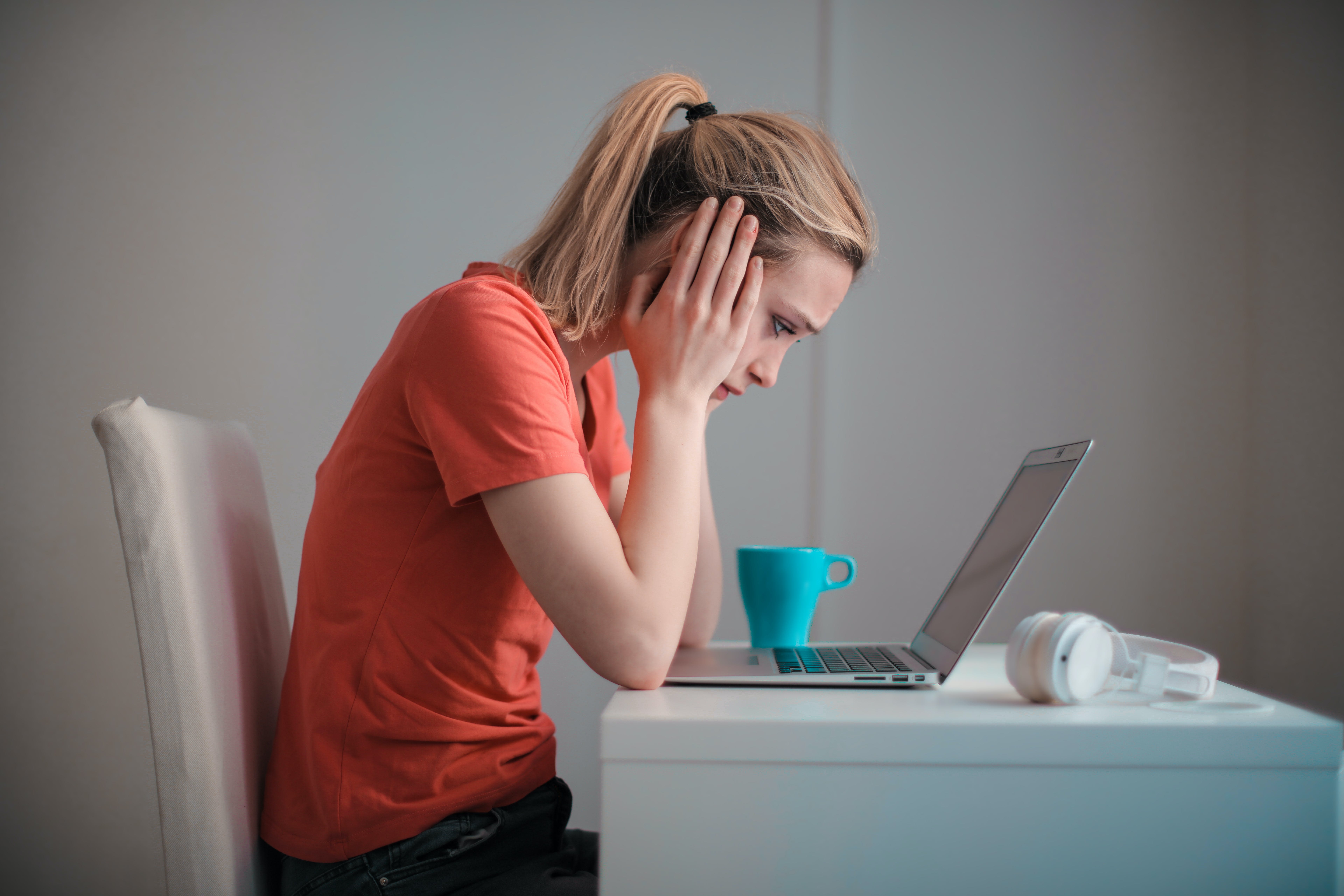 Woman holding her head in front of a computer